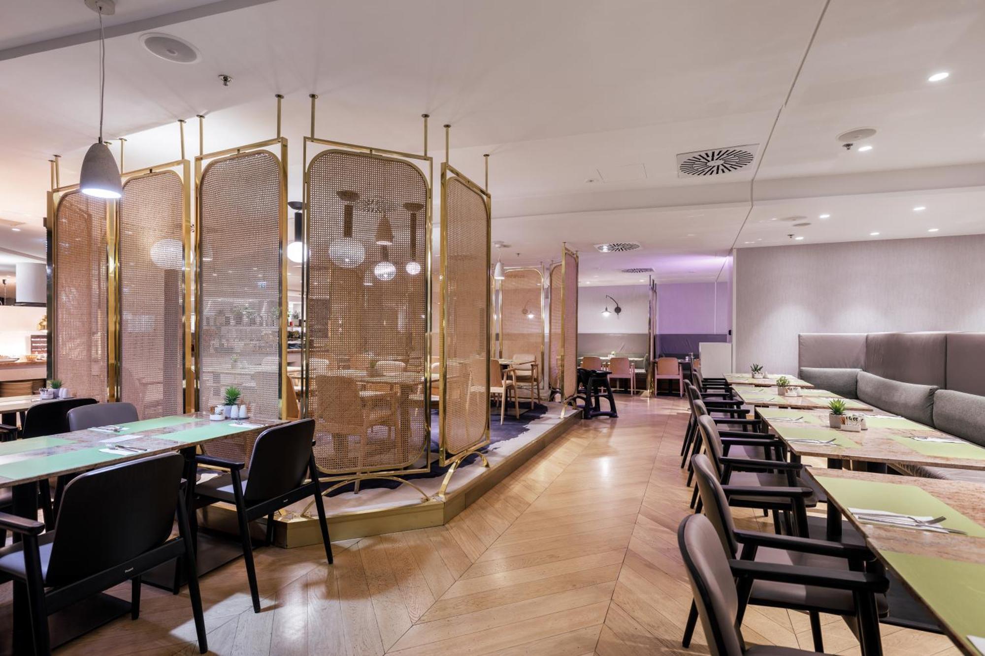 Radisson Blu Resort Świnoujście Εξωτερικό φωτογραφία The photo depicts a modern restaurant interior. It features a layout with several tables and chairs arranged in an organized manner. There is a decorative partition made of delicate mesh or fabric, providing some privacy between different dining area