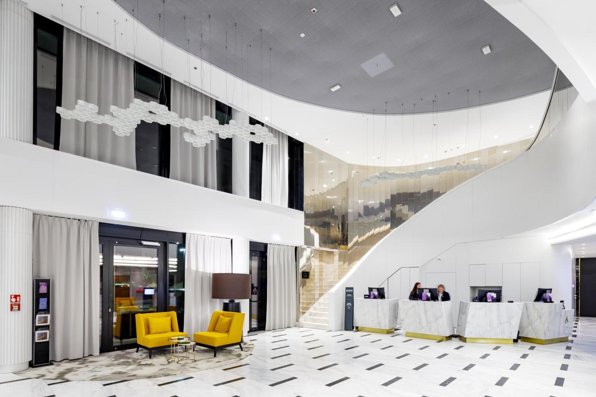 Radisson Blu Resort Świnoujście Εξωτερικό φωτογραφία The photo shows a modern interior space, likely a hotel or a lobby area. It features a spacious, open design with high ceilings and a stylish staircase that leads to an upper level. The walls are mostly white, with large windows allowing natural ligh