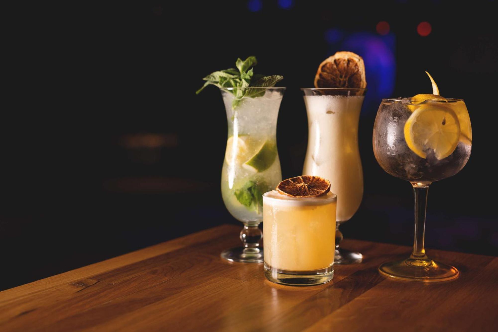 Radisson Blu Resort Świnoujście Εξωτερικό φωτογραφία The photo showcases a collection of four different cocktails displayed on a wooden table. 

1. **Mojito**: A tall glass filled with lime slices, mint leaves, and a clear liquid, likely rum-based, garnished with fresh mint.
2. **Creamy Cocktail**: A s