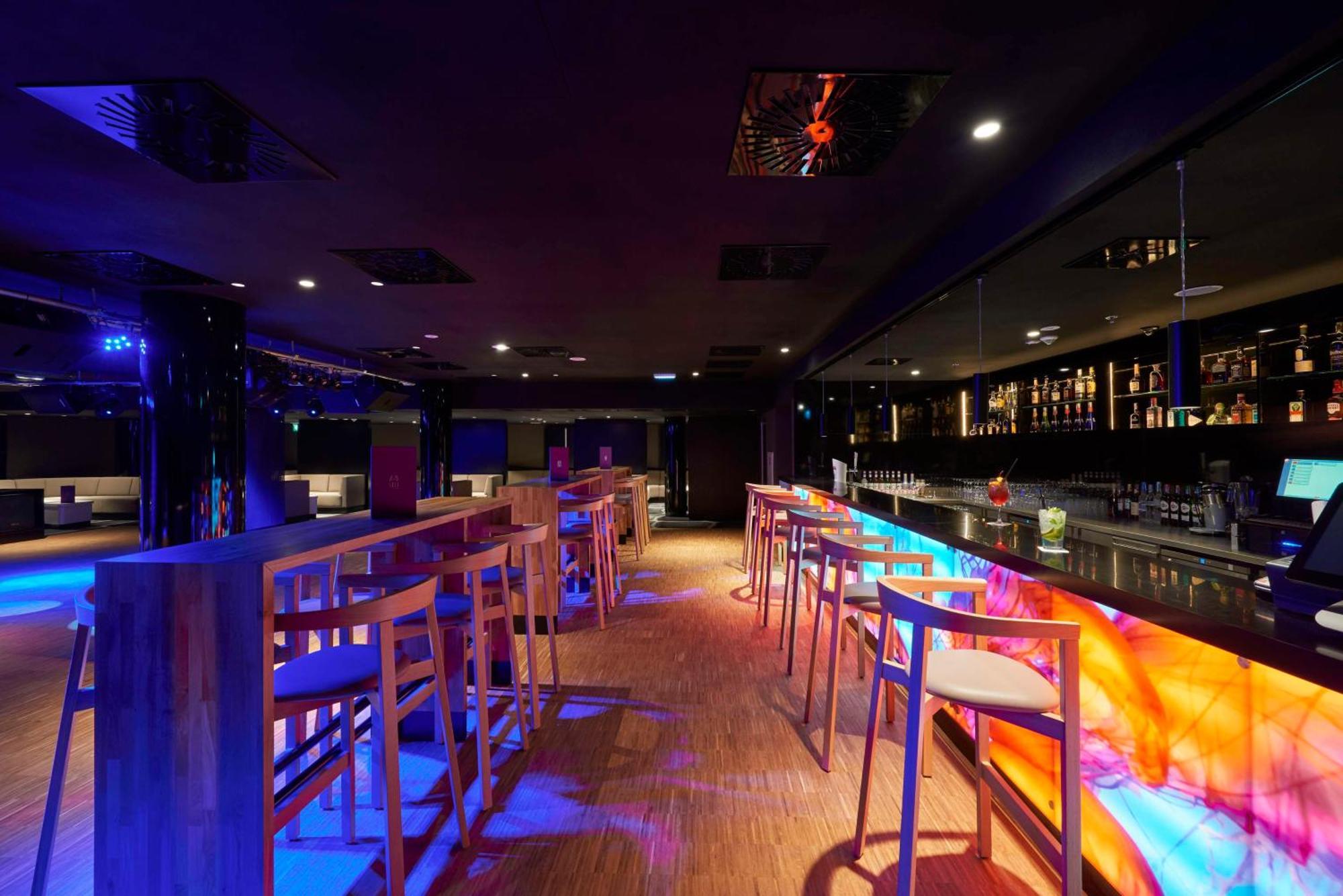 Radisson Blu Resort Świnoujście Εξωτερικό φωτογραφία The photo depicts a modern bar interior with a sleek and contemporary design. There are high wooden stools positioned along a bar counter, which features vibrant, colorful lighting underneath. The bar area is dimly lit, creating a nightlife ambiance,