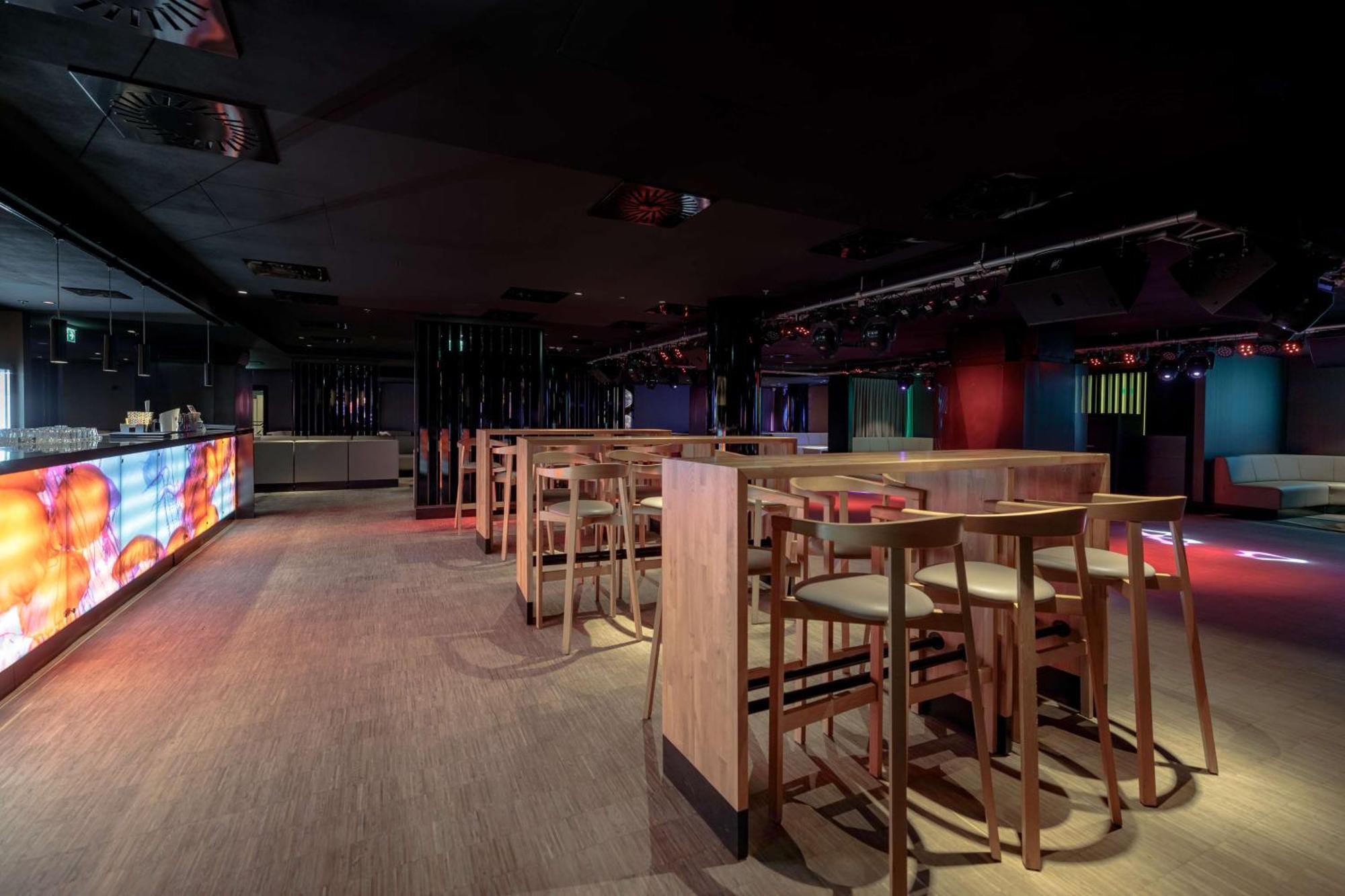 Radisson Blu Resort Świnoujście Εξωτερικό φωτογραφία The photo shows an interior space that appears to be a bar or lounge. It features a modern design with a dark color scheme. There are several wooden high-top tables with matching stools arranged in the area. In the background, there is a bar counter,