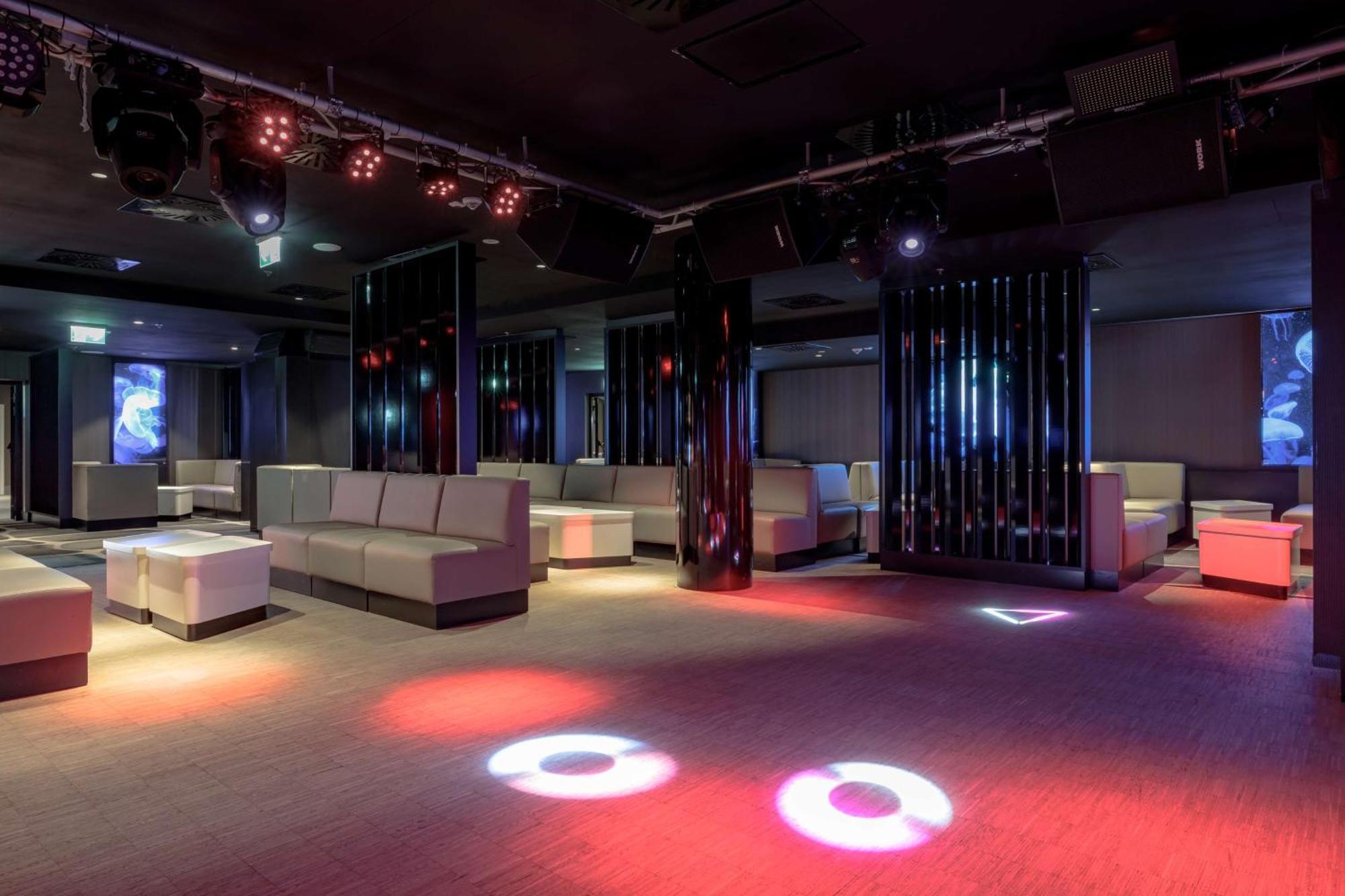 Radisson Blu Resort Świnoujście Εξωτερικό φωτογραφία The photo depicts a modern nightclub interior, featuring a spacious layout with sleek, minimalist seating arrangements. The room has plush seating along the walls, and the floor is illuminated with circular lights in varying colors, creating a vibran
