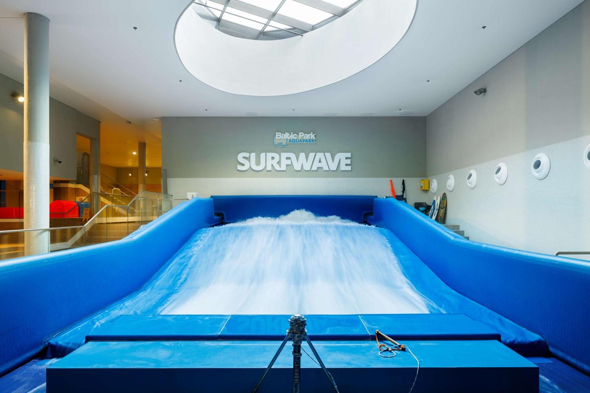 Radisson Blu Resort Świnoujście Εξωτερικό φωτογραφία The photo shows an indoor surfing attraction called "Surfwave." It features a large blue ramp with water flowing down it, creating a wave-like effect for surfing. Above the ramp, there is a sign that says "SURFWAVE." The area appears well-lit and mod